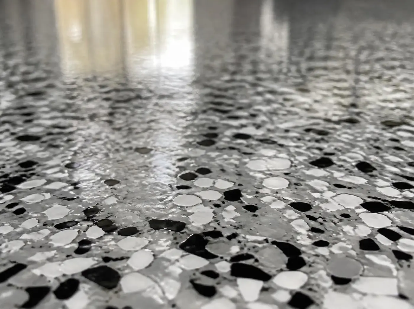 Close-up of a glossy black, gray and white flake epoxy garage floor